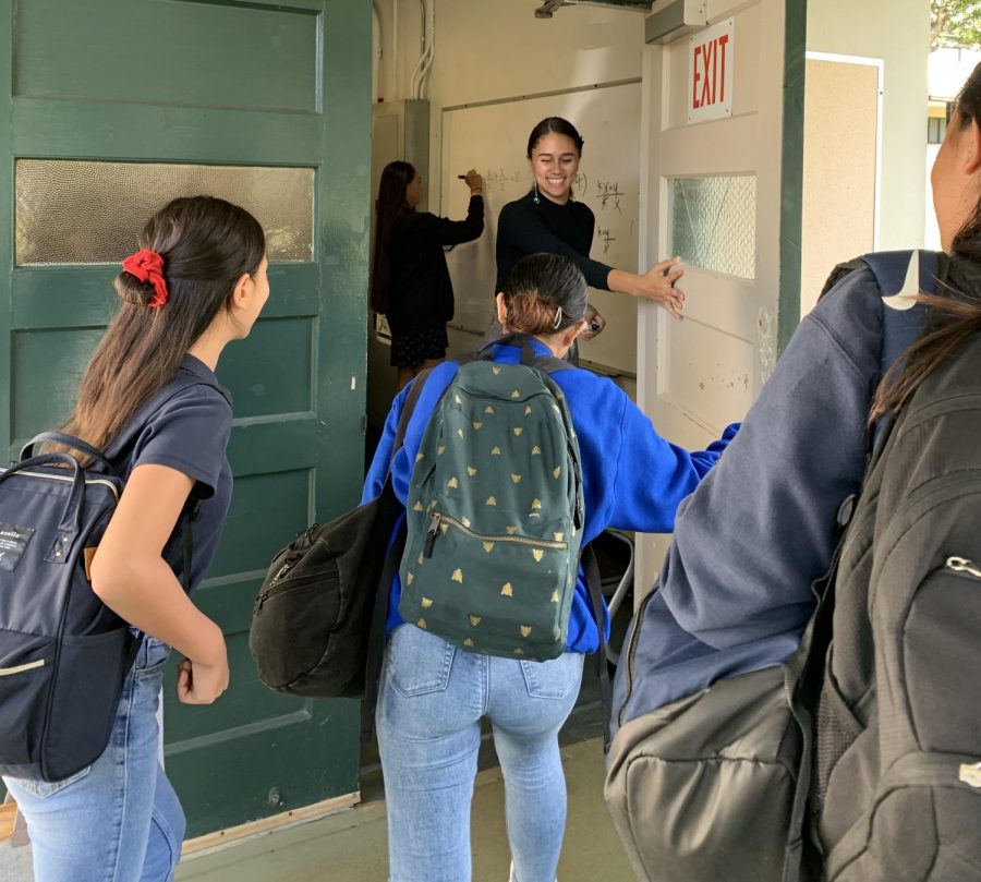 Junior Sarae Miguel opens the door and welcomes 8th graders to the Algebra 2 classroom. 