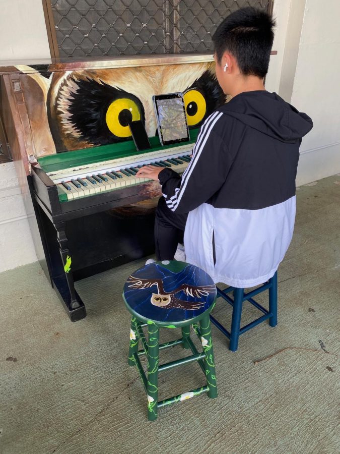 Student playing new piano outside the cafeteria. 