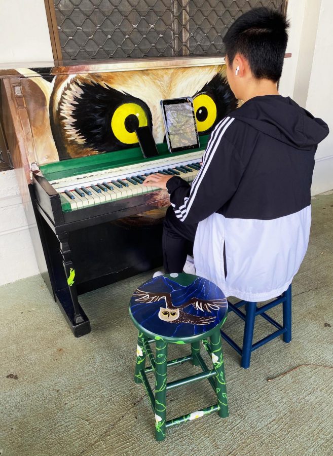 Student playing new piano outside the cafeteria. 