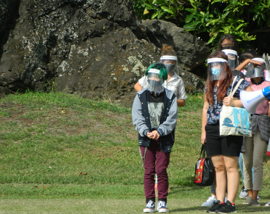 Students at the freshman orientation standing with their cohorts wearing masks and face shields on the football field. Mid-Pacific brought back high school students to campus with some staying virtual for the remainder of the semester.