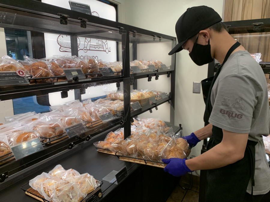 Senior Chris Wong puts down a tray of baked goods at his part time job. Students have continued to find ways to make money through a part time job or creating their own side businesses.