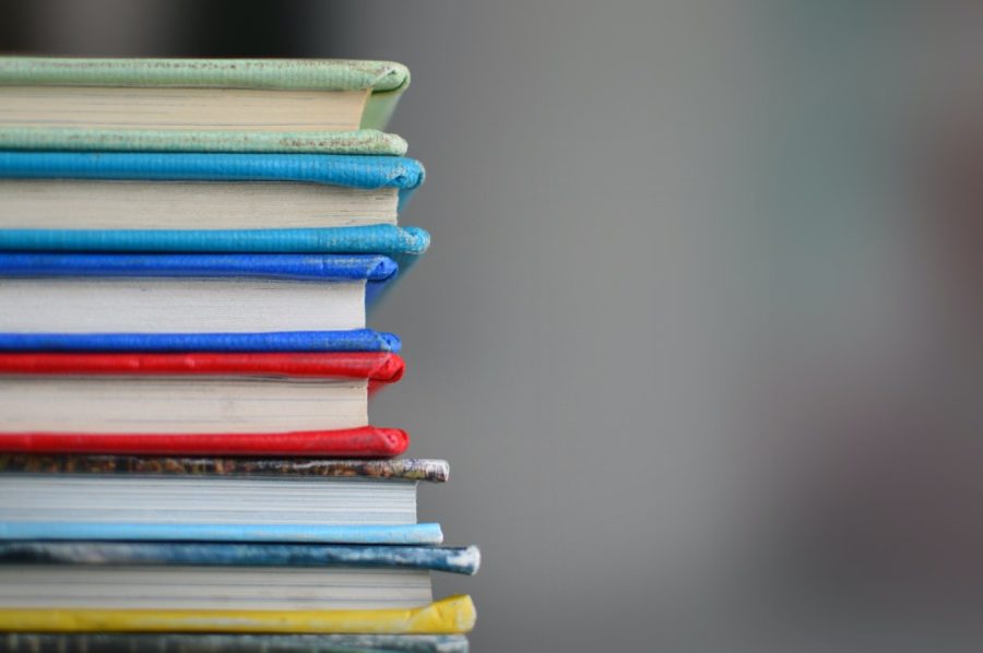 Colorful rainbow of books stacked high for reading. 