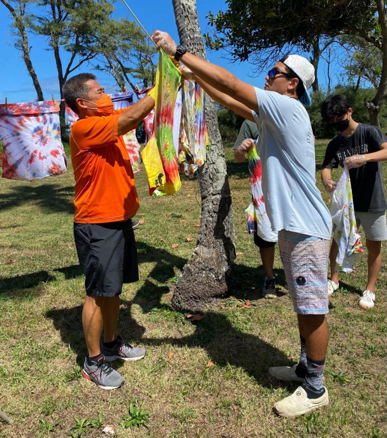 Derrick Kang, director of college counseling and senior Kama Higa hangs Higa's tie-dye shirt at senior camp. Camp was an event primarily communicated about online. 