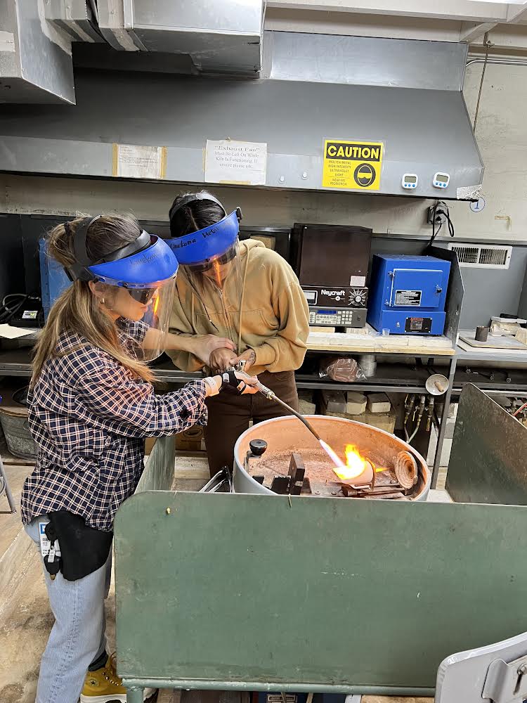 Annelise Yee assisting her student Nellie complete a bronze casting in a centrifuge.