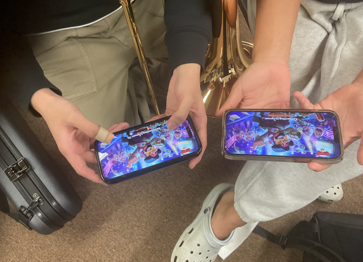 Two students play Brawl Stars during their free time in the band room.