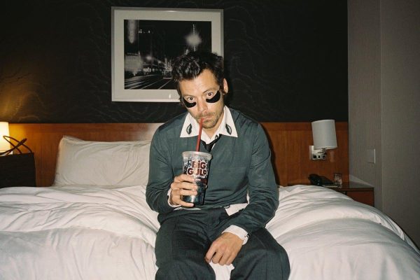 Harry Styles sitting in hotel room, drinking a Big Gulp and being iconic